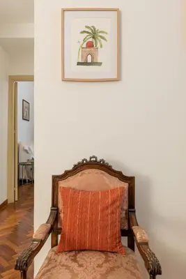 a bed with an orange pillow against a white wall at Casa Marettu in Palermo
