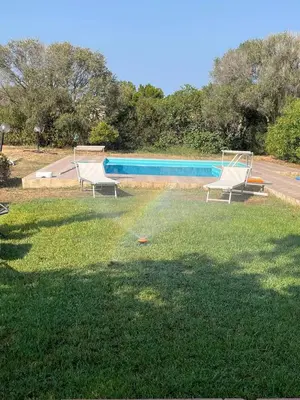 a pool with two chairs and a rainbow in the grass at Villacinisi in Cinisi