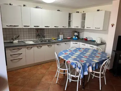 a kitchen with a table and chairs and white cabinets at Villacinisi in Cinisi