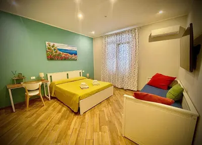 a bedroom with a bed and a table and a desk at Casa Batù alle porte del Capo in Palermo