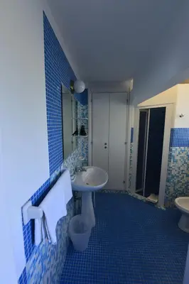 a blue tiled bathroom with a sink and a toilet at Miss Sicily B&B in Terrasini