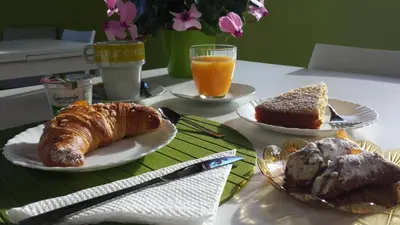 a table with two plates of food and orange juice at Miss Sicily B&B in Terrasini