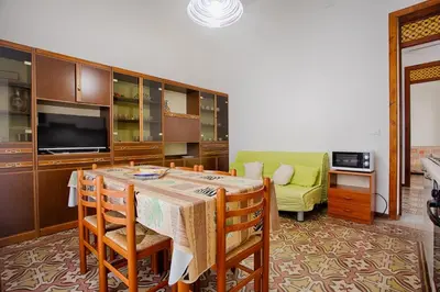 a kitchen with a table and chairs and a couch at GuestHost - Castellammare Stella Apartments in Castellammare del Golfo