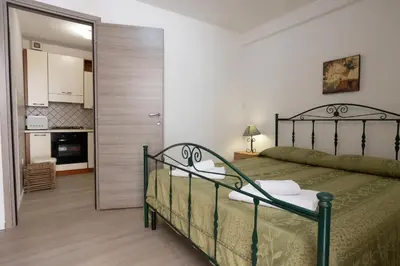 a bedroom with a bed and a door leading to a kitchen at GuestHost - Castellammare Stella Apartments in Castellammare del Golfo