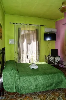 a green bed in a room with a window at L' Arco Antico in Caccamo