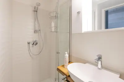 a white bathroom with a shower and a sink at Casa Azul alla Cala by Wonderful Italy in Palermo