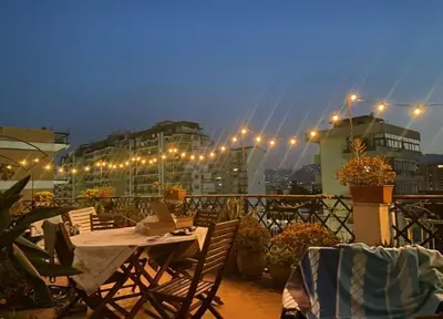 a patio with tables and chairs on a balcony with lights at MONTE PELLEGRINO HOUSE AND TERRACE in Palermo