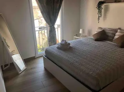 a bedroom with a bed and a large window at Appartamento NA ME CASA in Palermo