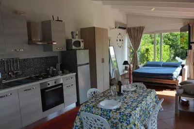 a kitchen with a table and a room with a bed at La casetta nel verde in Palermo