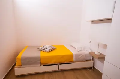 a small bedroom with a bed with a yellow blanket at White Home in Castellammare del Golfo