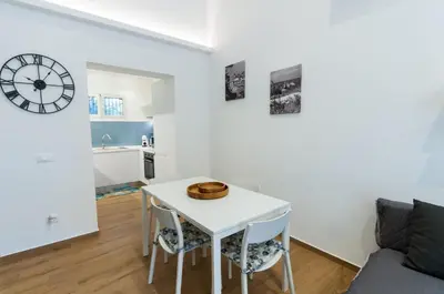 a white table and chairs in a living room with a clock at White Home in Castellammare del Golfo