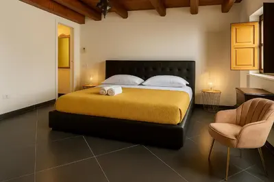 a bedroom with a large bed and a chair at La Residenza dell' Alloro in Palermo