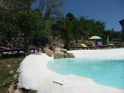 a swimming pool with chairs and an umbrella at Villa Paladino Solunto in Santa Flavia