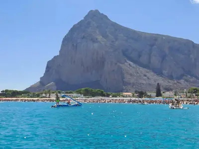 a group of people on a beach with a mountain in the background at Appartamento Dolceluna in San Vito lo Capo