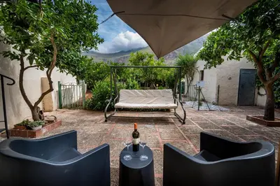 a patio with a couch and a table with a bottle of wine at La Casetta in San Vito lo Capo