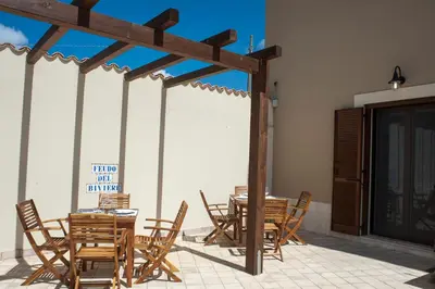 a patio with wooden tables and chairs on a patio at Feudo Del Biviere in Santa Ninfa
