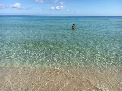 a man standing in the water at the beach at Villa Le Lanterne Pool & Relax in Mondello