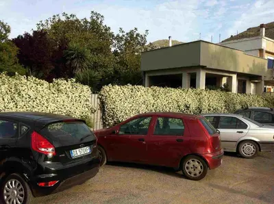 three cars parked in a parking lot next to a fence at Villa Le Lanterne Pool & Relax in Mondello