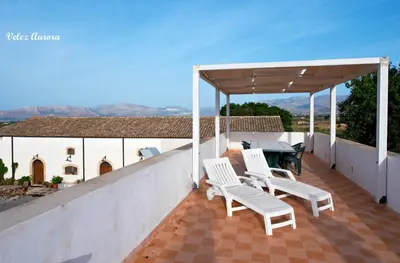 a patio with white chairs and a table on a roof at Baglio 