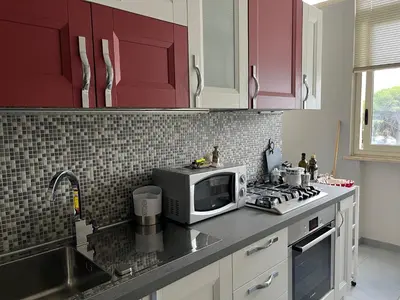 a kitchen with red cabinets and a microwave and a sink at Wave house in Palermo