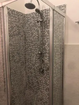 a shower with a glass door with a shower head at Serradifalco Cozy House di Enza e Luigi in Palermo