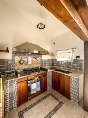 a kitchen with wooden cabinets and a stove top oven at Casetta della Muri in Isola delle Femmine