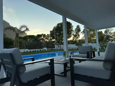 a patio with a table and chairs and a pool at Villa dei Pioppi Deluxe in Carini