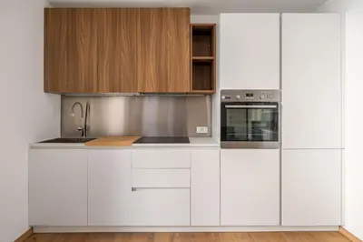 a white kitchen with wooden cabinets and a sink at Little House Mavi by DomuSicily in Palermo