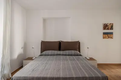 a bedroom with a large bed in a white wall at Little House Mavi by DomuSicily in Palermo