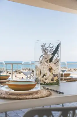 a table with wine glasses and a plate of food on the beach at Villa sulla spiaggia Riva Estate by Le Dhome Sicily in Trappeto