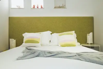 a bed with white pillows and a green headboard at Villa sulla spiaggia Riva Estate by Le Dhome Sicily in Trappeto