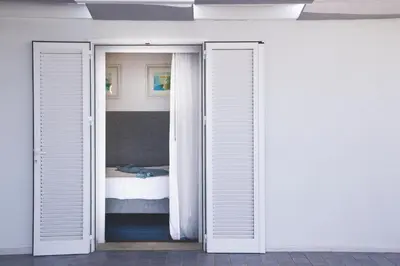 a bedroom with two doors leading to a bed at Villa sulla spiaggia Riva Estate by Le Dhome Sicily in Trappeto