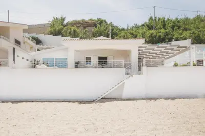 a house on the beach with white walls and sand at Villa sulla spiaggia Riva Estate by Le Dhome Sicily in Trappeto