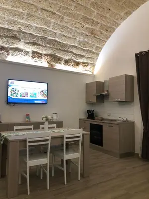 a kitchen with a table and chairs and a tv on the wall at Le Antiche Alcove in Terrasini