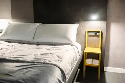 a bed with a yellow night stand next to it at Alma Hotel in Palermo