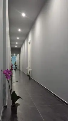 a hallway with white walls and purple flowers in a vase at Alma Hotel in Palermo