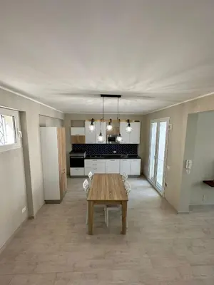 a living room with a table and a kitchen at The White Lodge in Porticello