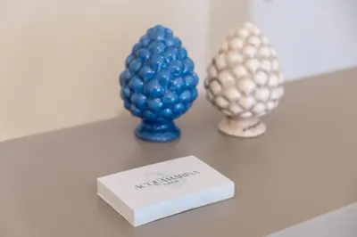 a table with two blue vases and a book at Acquamarina Rooms in Castellammare del Golfo