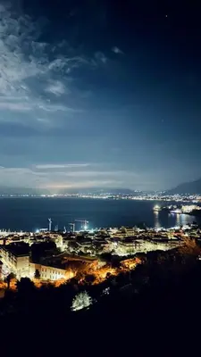 a view of a city and the ocean at night at The White Lodge in Porticello