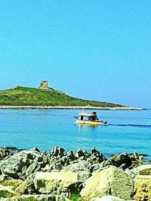 a boat in the water with an island in the background at Sicilia House bluchic in Isola delle Femmine