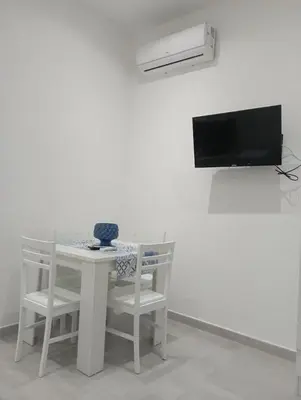 a white table with two chairs and a television at Sicilia House bluchic in Isola delle Femmine