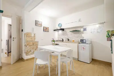 a white kitchen with a white table and chairs at Talia Capo Massimo in Palermo
