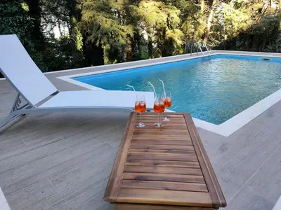 two wine glasses on a table next to a swimming pool at Villa Calici in Pioppo