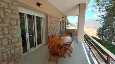 a patio with a wooden table and chairs on a balcony at Villa Calici in Pioppo
