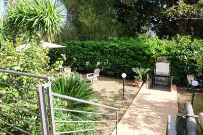 a garden with chairs and plants and a fence at Grande Villa con Giardino e BBQ vicino al Mare in Mondello