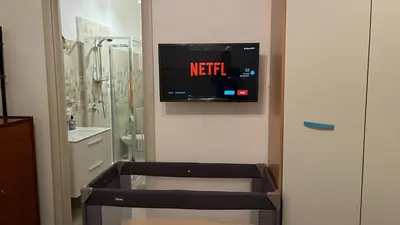 a bathroom with a tv on the wall next to a toilet at Casa Lo Re in Bagheria