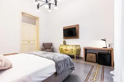 a white bedroom with a bed and a desk at Kepos Rooms and Suites in Palermo