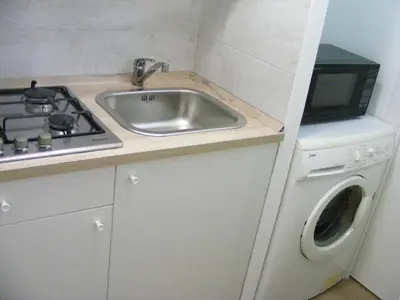 a kitchen with a sink and a stove and a washing machine at Makihome in Palermo