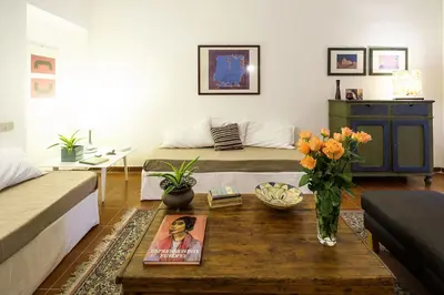 a living room with a bed and a table with flowers at At Kalsa Quiet Flowered Terrace! Free Parking! Ideal for remote working! in Palermo