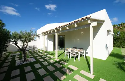 a white house with a table and chairs in a yard at Villa Charme in San Vito lo Capo
